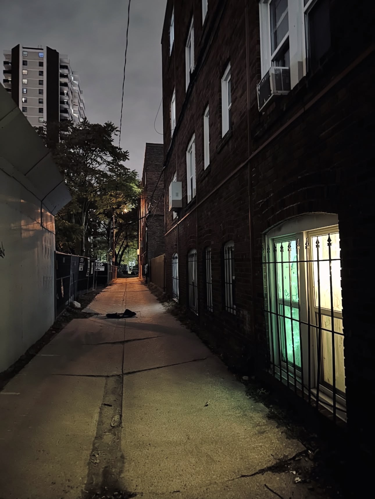 Toronto alley at night with glowing green window