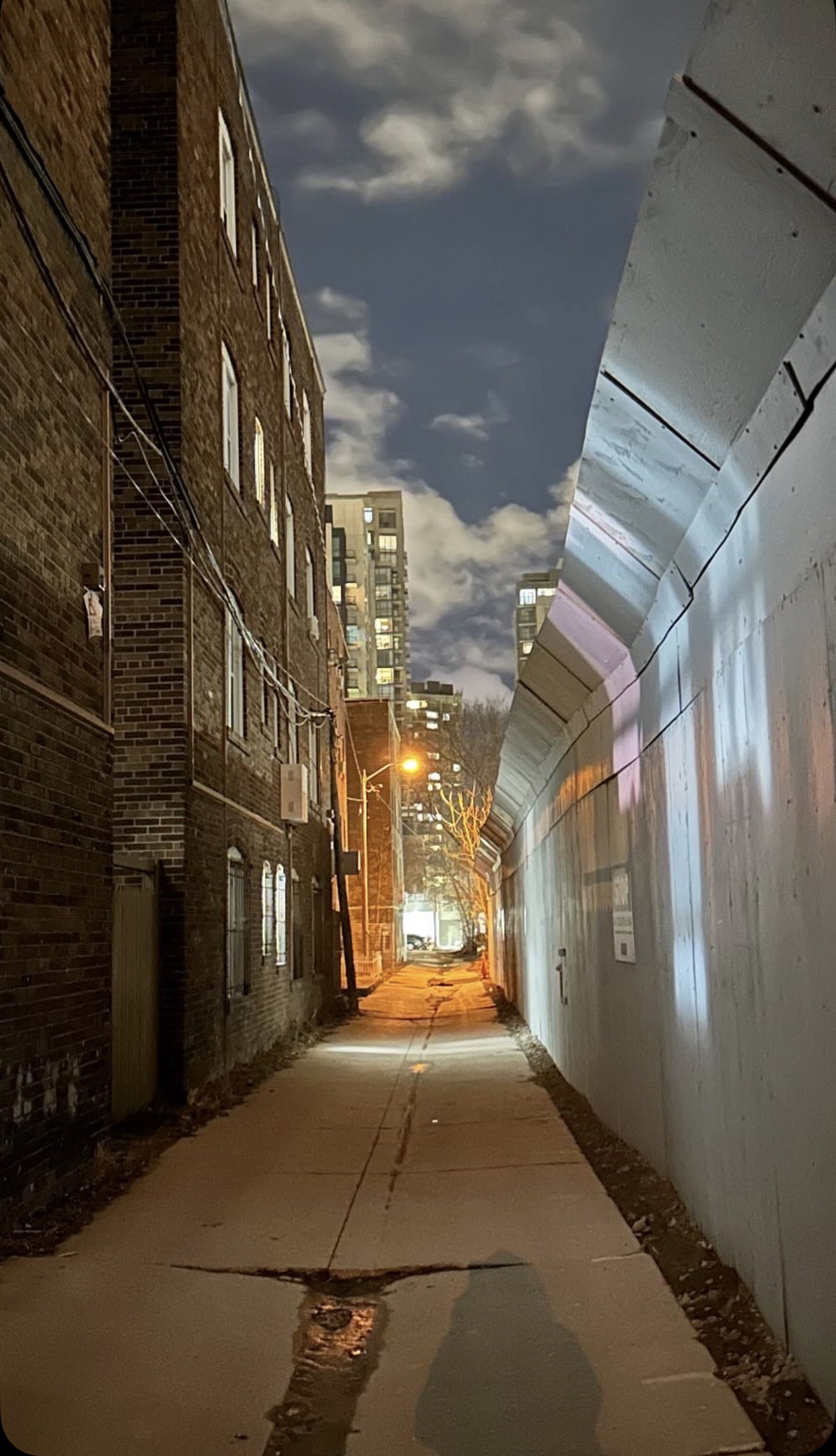 Toronto alley at night with large construction hoarding wall