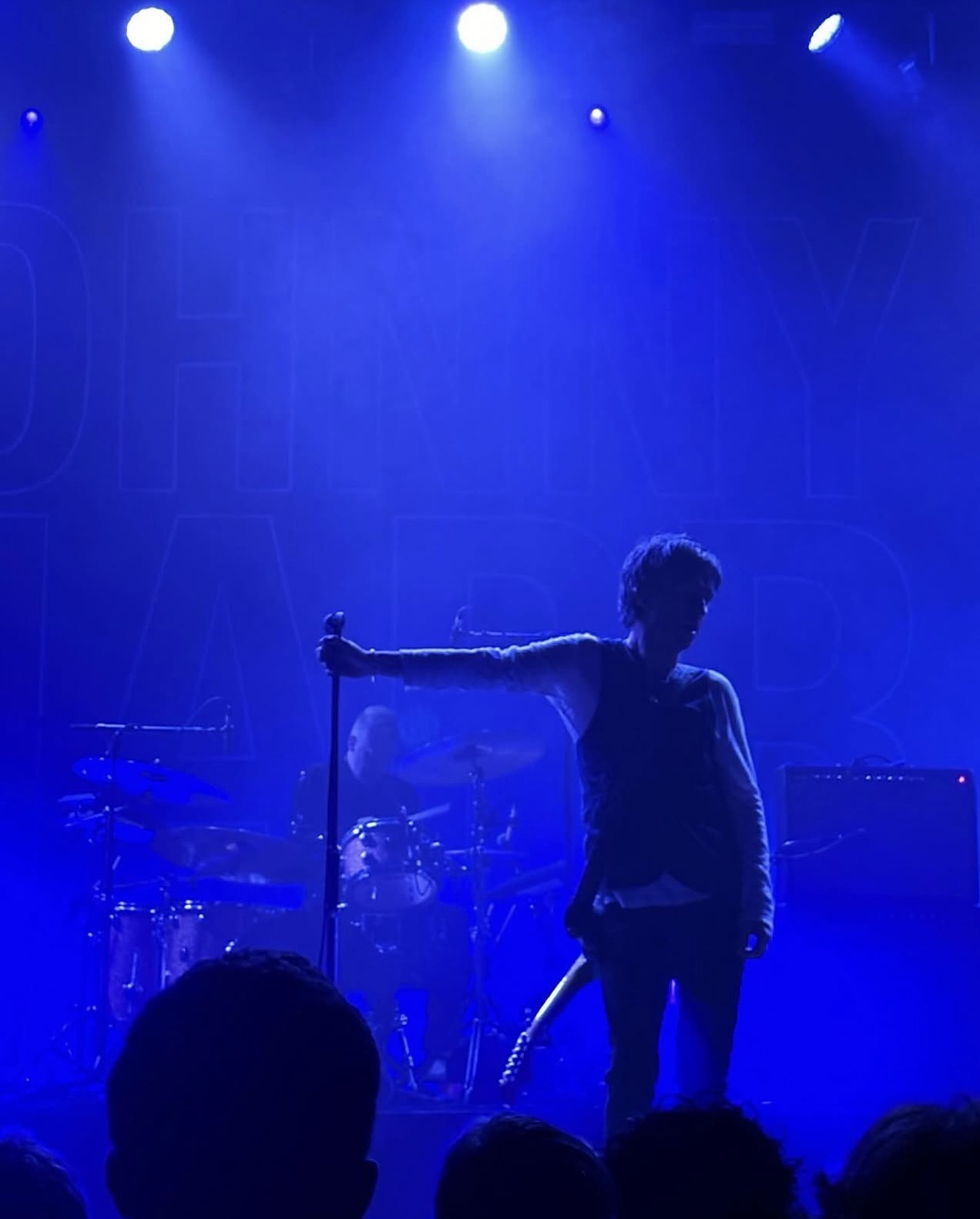 Silhouetted guitarist on stage bathed in blue light