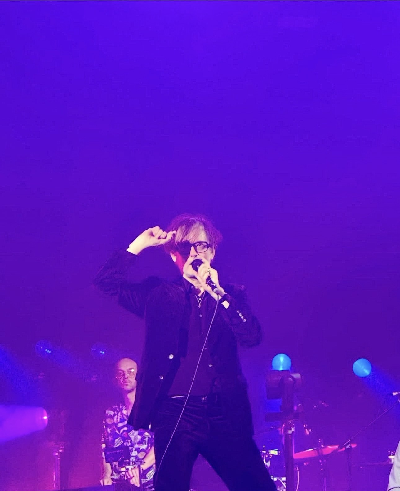 Jarvis Cocker performing on stage in purple light